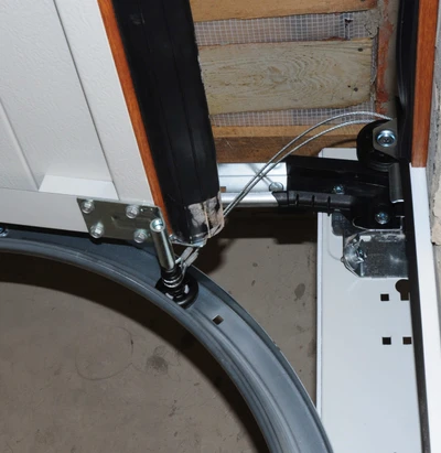 Professional garage door technician replacing damaged lift cables showing frayed cable repair work near garage door drum and pulley system with proper safety equipment for reliable door operation in Cincinnati homes
